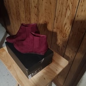 A pair of burgundy wedge boots.